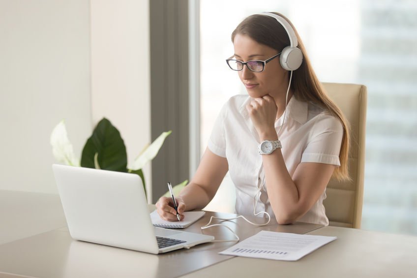 Woman with headphones on watching video on laptop